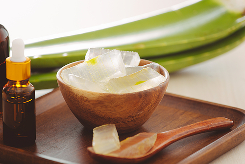 bottle of aloe vera essential oil with peeled aloe and leaves - beauty treatment