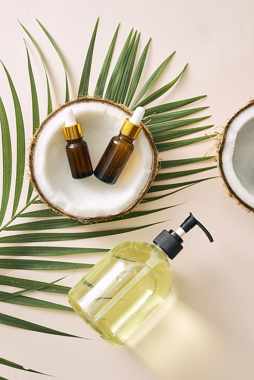 Cracked coconut and a bottle of oil on the table - spa, skincare, haircare and relaxation concept