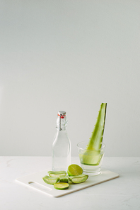 fresh aloe vera leaves and glass bottle on white background