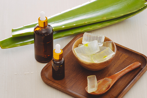 bottle of aloe vera essential oil with peeled aloe and leaves - beauty treatment