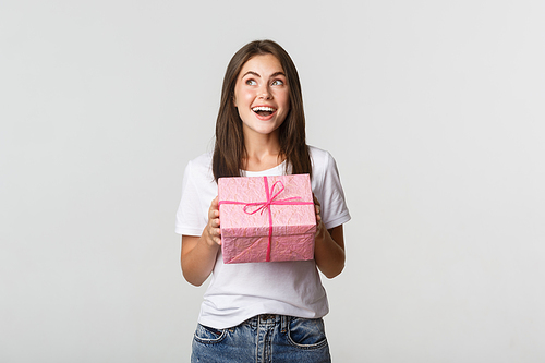 Surprised happy birthday girl receiving wrapped gift, white background.