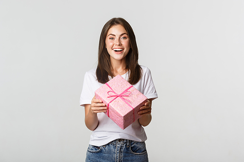 Attractive happy brunette girl holding birthday gift and smiling cheerful.