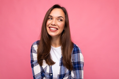 photo portrait of young beautiful smiling hipster brunette woman in trendy blue and white shirt.  carefree female person posing isolated near pink wall with empty space in studio. positive model.