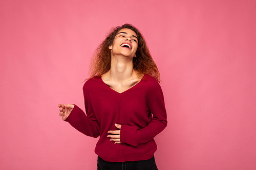 Photo of young happy positive pretty nice brunette wavy woman with sincere emotions wearing casual pink sweater isolated over pink background with empty space and laughing.
