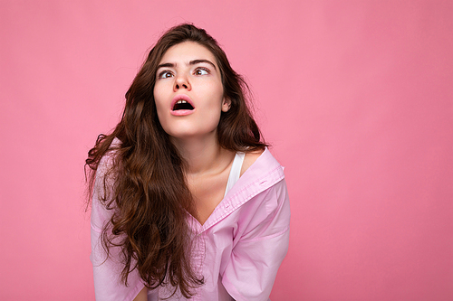 Portrait of beautiful tired emotional exhausted young curly brunette woman wearing pink shirt and grey hat isolated on pink background with copy space.