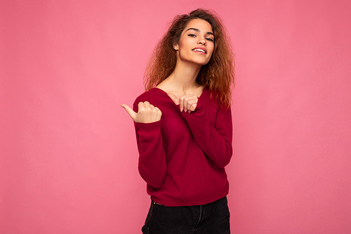 Portrait of beautiful fascinating emotional positive joyful happpy female promoter pointing to the side at copy space for advertising wearing hipster outfit isolated over background wall with empty space with sincere emotions.