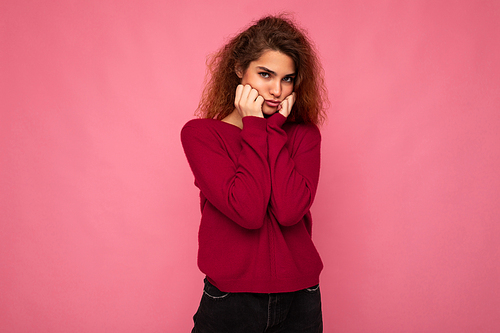 Portrait of young emotional offended touchy beautiful brunette curly woman with sincere emotions wearing trendy pink pullover isolated on pink background with copy space and taking offence.