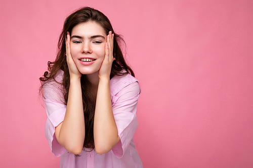 photo of young beautiful happy smiling curly brunette woman wearing pink shirt.  carefree female person posing isolated near pink wall in studio with free space. positive model with natural makeup.