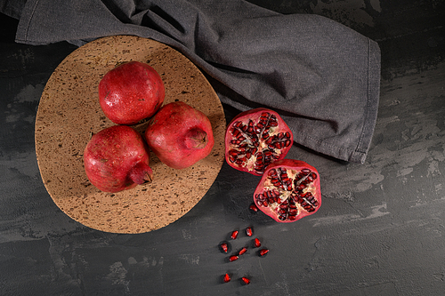 ripe pomegranate fruit and pomegranate seeds on dark background, close-up. healthy vegetarian antioxidant organic weight loss food