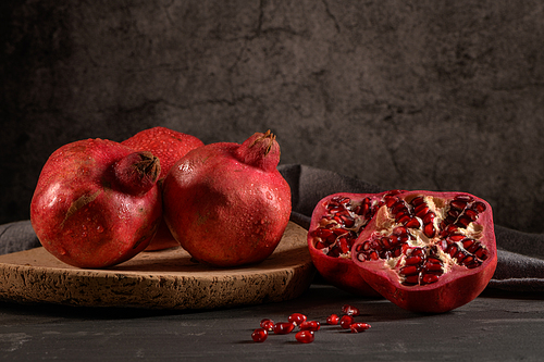 ripe pomegranate fruit and pomegranate seeds on dark background, close-up. healthy vegetarian antioxidant organic weight loss food