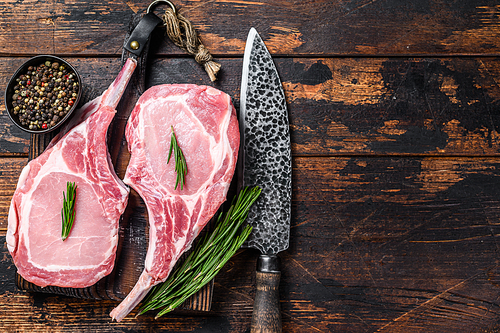 Marbled raw pork chops meat steak or tomahawk. Dark wooden background. Top view. Copy space.
