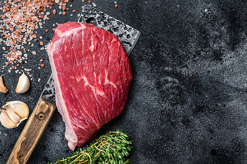 Fresh Raw rump beef cut or top sirloin cap steak on butcher cleaver. Black background. Top view. Copy space.