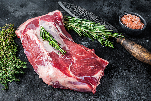Fresh Raw lamb mutton shoulder meat with butcher knife. Black background. Top view.