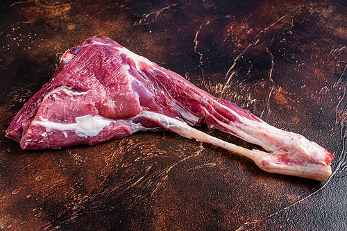 Whole raw lamb leg meat on the bone. Dark background. Top view.