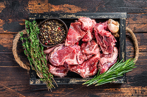 Raw lamb or goat meat diced for stew with bone. Dark wooden background. Top view.