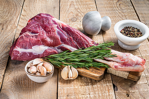 Fresh Raw lamb or goat leg with rosemary and pepper on cutting board. wooden background. Top view.