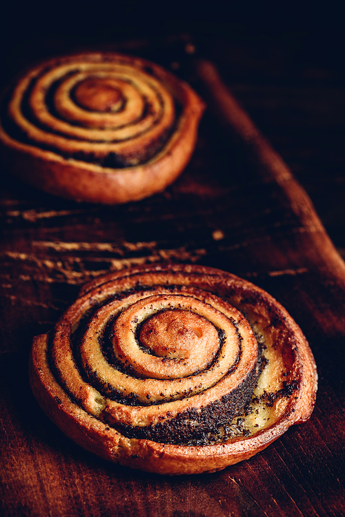 Sweet roll with poppy seeds on rustic wooden surface