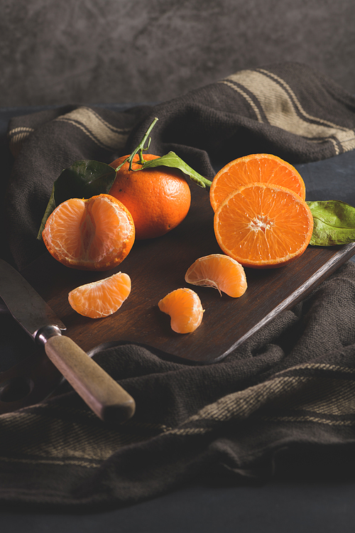 Fresh mandarin oranges or tangerines with leaves on textured dark background