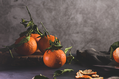 Fresh mandarin oranges or tangerines with leaves on textured dark background