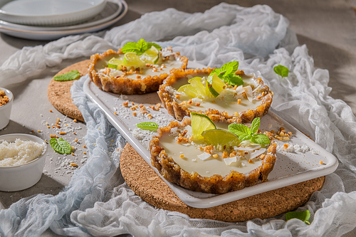 Lime vegan tarts with grated coconut  and crunchy peanuts. Citrus cake. Date, walnut, almond and hazelnut base.