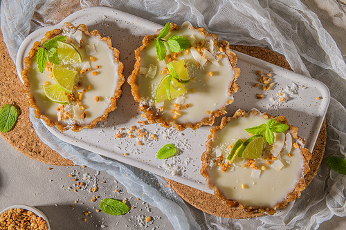 Lime vegan tarts with grated coconut  and crunchy peanuts. Citrus cake. Date, walnut, almond and hazelnut base.
