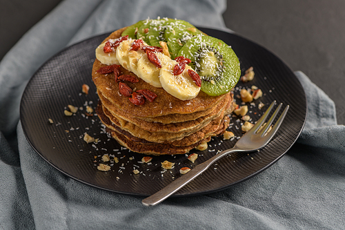 Healthy breakfast table,  homemade pancakes with kiwi, banana, goji and walnuts.