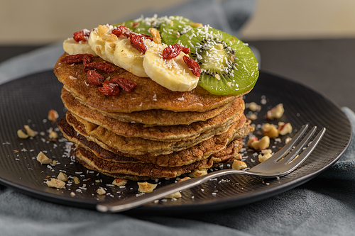 Healthy breakfast table,  homemade pancakes with kiwi, banana, goji and walnuts.