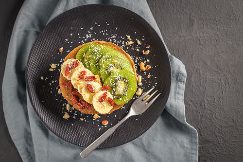 Healthy breakfast table,  homemade pancakes with kiwi, banana, goji and walnuts.