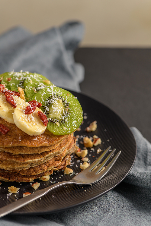 Healthy breakfast table,  homemade pancakes with kiwi, banana, goji and walnuts.