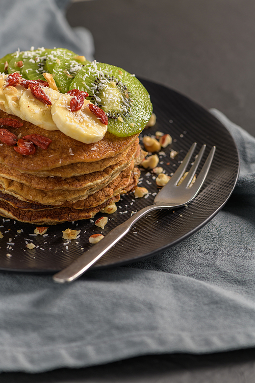 Healthy breakfast table,  homemade pancakes with kiwi, banana, goji and walnuts.