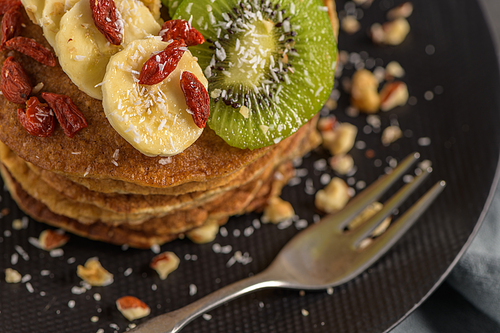 Healthy breakfast table,  homemade pancakes with kiwi, banana, goji and walnuts.