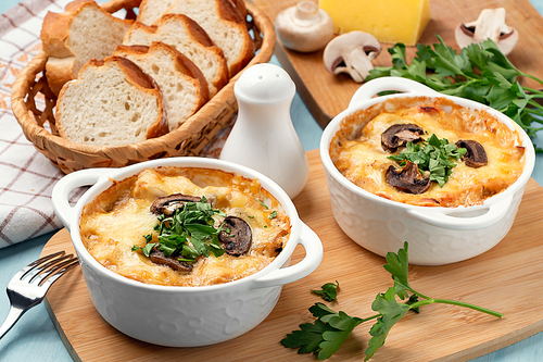 Casserole with chicken, mushrooms and cheese, known in Russia as julienne in white bowls with herbs.