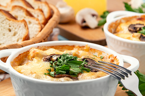Casserole with chicken, mushrooms and cheese, known in Russia as julienne in white bowls with herbs, close up.