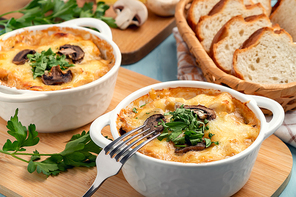 Casserole with chicken, mushrooms and cheese, known in Russia as julienne in white bowls with herbs.