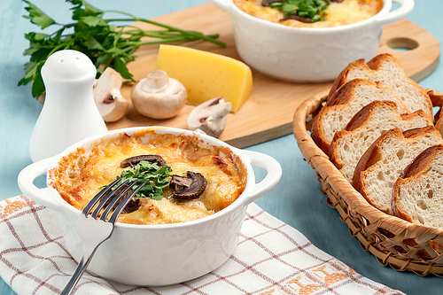 Casserole with chicken, mushrooms and cheese, known in Russia as julienne in white bowl with herbs.