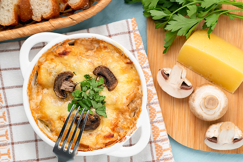 Casserole with chicken, mushrooms and cheese, known in Russia as julienne in white bowl with herbs, top view, flat lay.