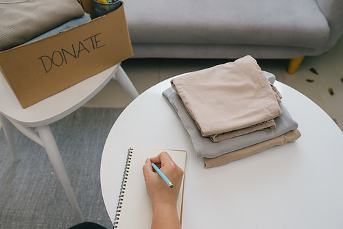 Volunteer writing in notebook and near carton box with clothes