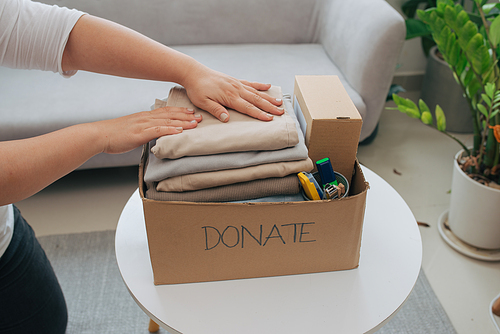 Close-up Of A Woman Putting Clothes Inside Donation Box