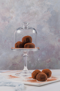 Cocoa balls, chocolate balls cakes in a glass stand, sprinkled with cocoa powder.