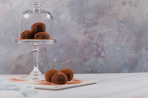 Cocoa balls, chocolate balls cakes in a glass stand, sprinkled with cocoa powder.