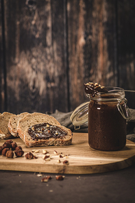 Vegan chocolate spread made of organic almond butter and organic cacao and honey, on dark rustic kitchen counter top.