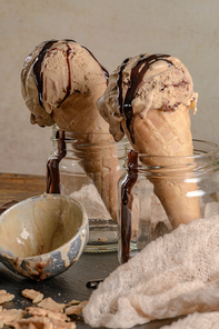 Homemade chocolate ice cream in waffle cones and pieces of dark chocolate.