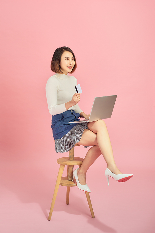 Beautiful woman holding credit card to payment online by her laptop.