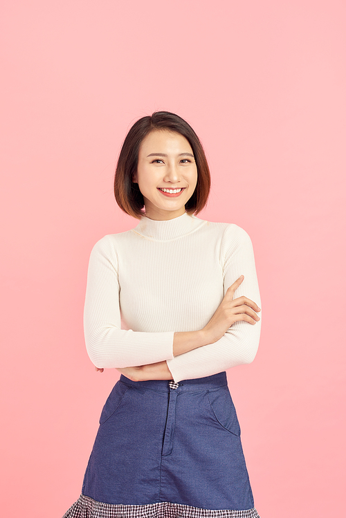 Young Asian woman wearing  sweater standing over isolated pink background happy face smiling with crossed arms looking at the camera. Positive person.