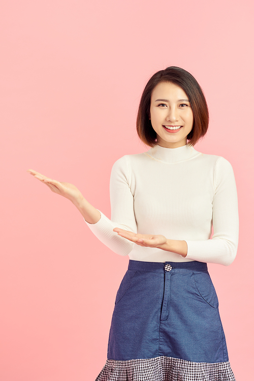 Beauty skincare Asian woman show something to you on the pink background