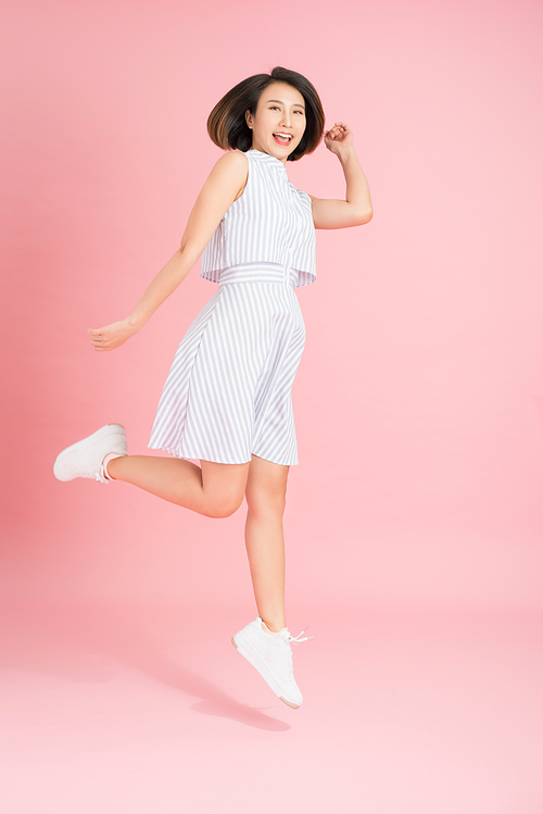 Freedom in moving. Surprised, pretty, happy young woman jumping and gesturing against pink studio background