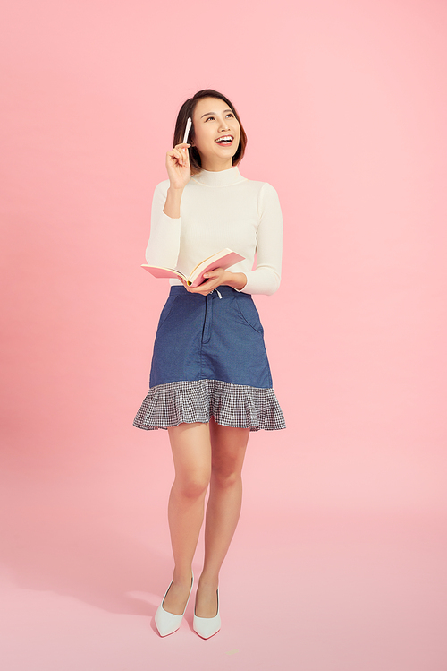 Full length portrait of a smiling beautiful woman holding isolated on a pink background.