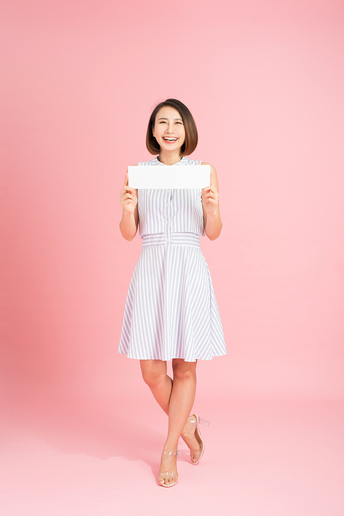 Attractive woman holding paper blank in her hands. Portrait of emotional young woman showing surprised and happy emotions