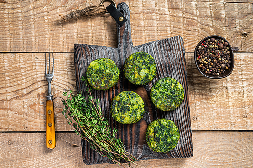 Vegetarian vegetable burgers patty with herbs on wooden board. Wooden background. Top view.
