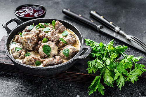 Swedish meatballs with lingonberry sauce in a frying pan. black background. Top view.